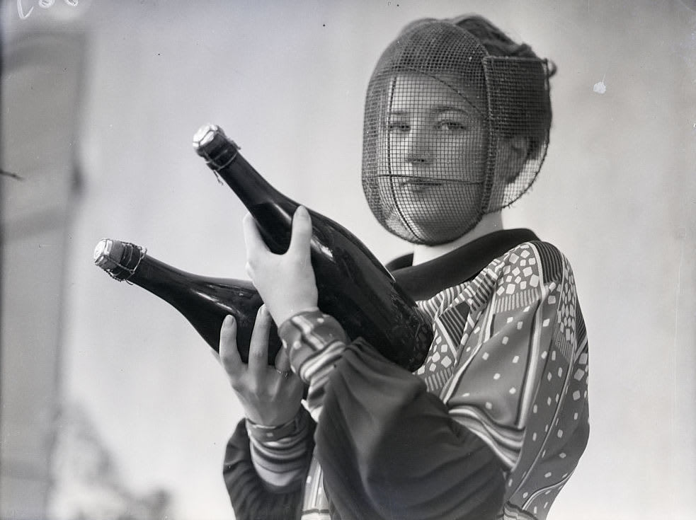 Amy Peterson wears a mask made of steel mesh to protect her from injury while she inspects champagne bottles, 1933 .