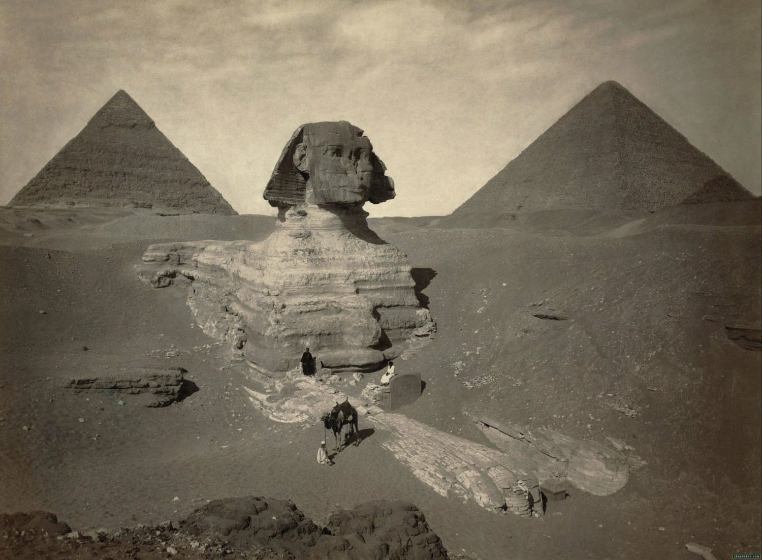 photo of the partially excavated Great Sphinx of Giza, with the Pyramid of Khafre (left) and the Great Pyramid of Giza (right) behind it. taken around 1878.