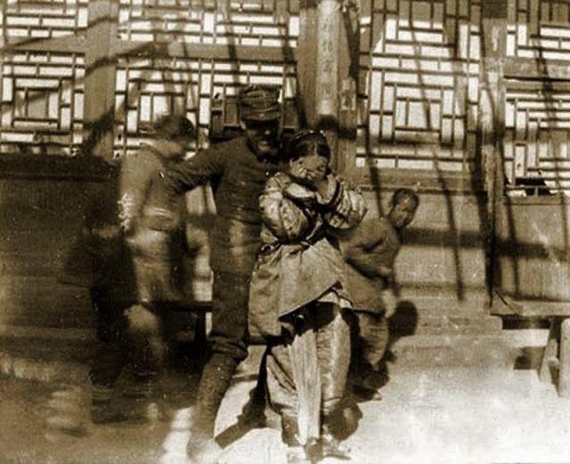 A soldier of the Eight Nation Alliance coerces a Chinese child into taking a photo with him. Boxer Rebellion, Beijing, 1900.