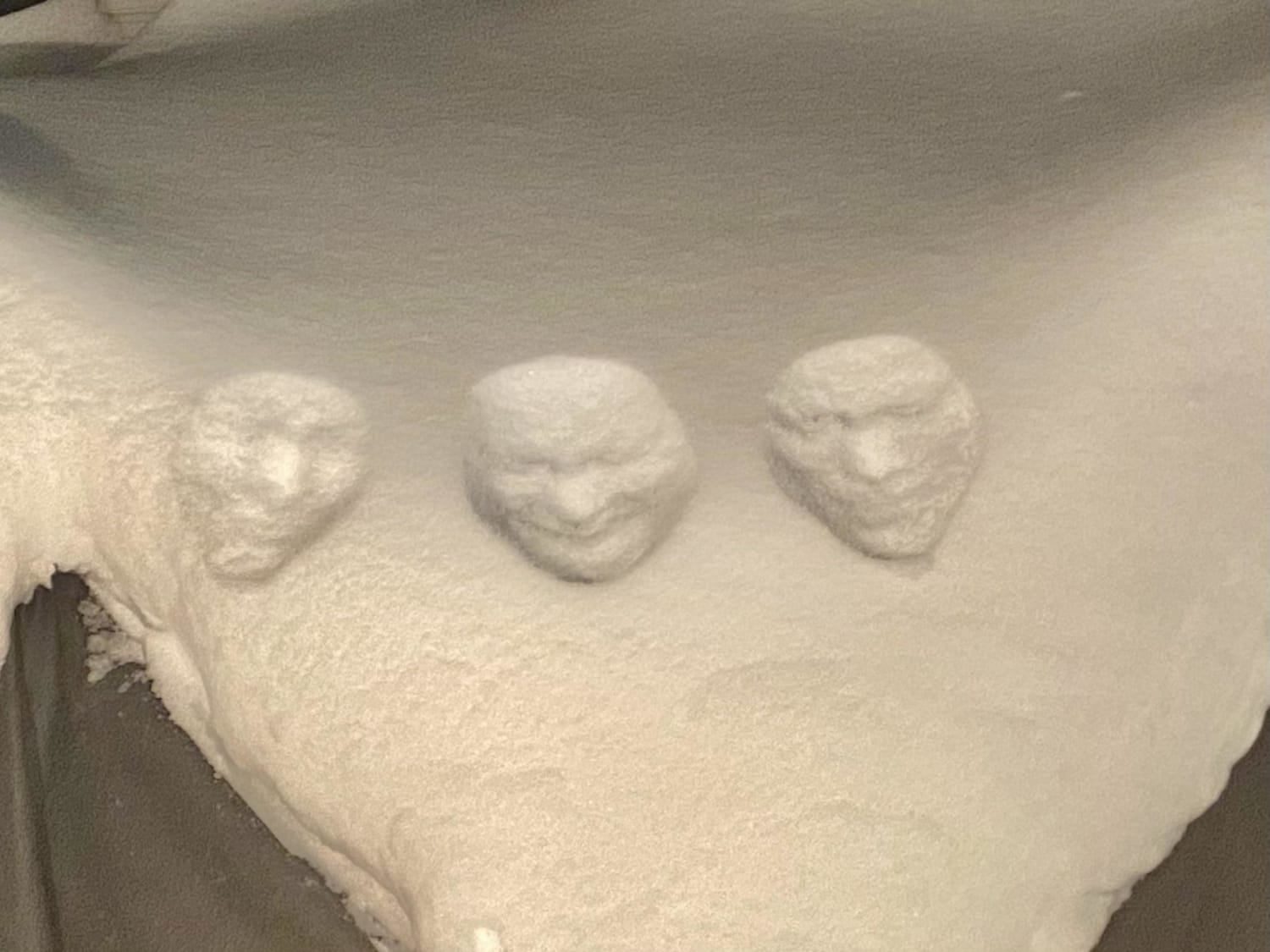 Face prints in the snow looking like they pop out towards you.