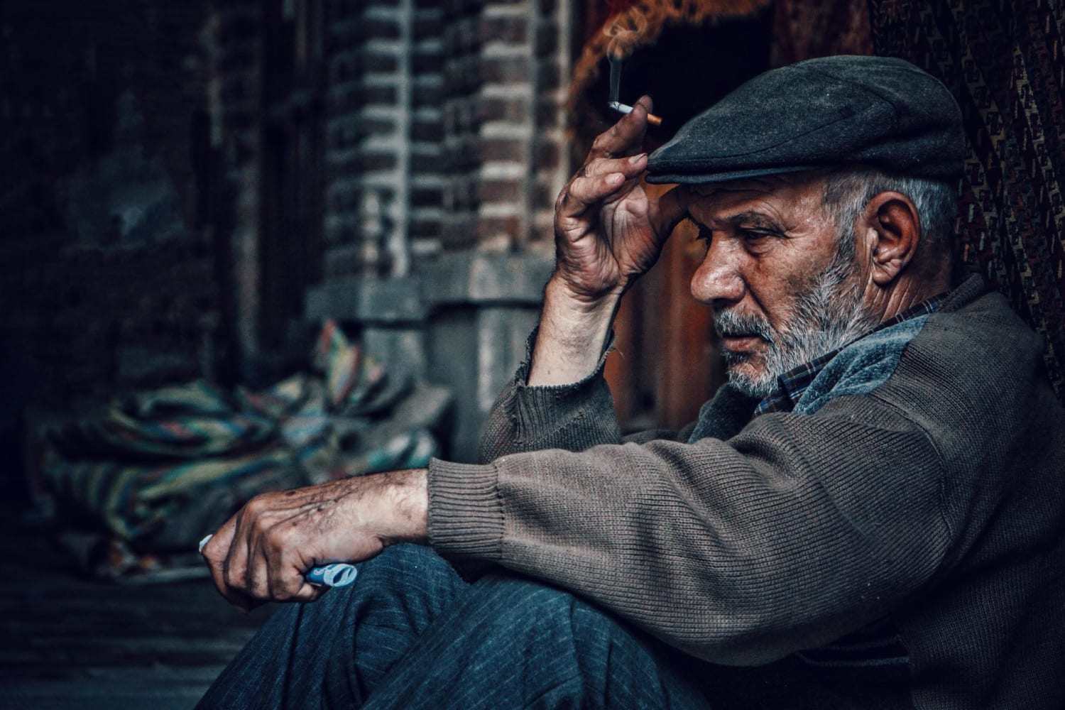 Tabriz Grand Bazaar, Tabriz, Iran. A man lit his cigarette and focused his eyes to infinity. He looked so tired and sad. Photographer Hasan Almasi.
