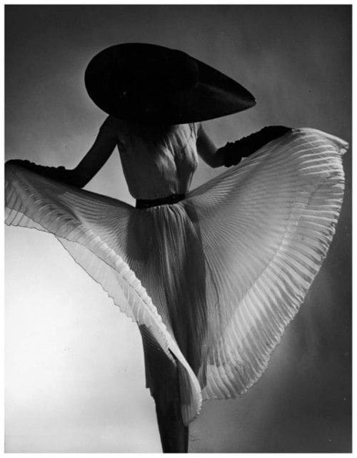 Model Dorian Leigh sporting black picture hat while showing off accordian pleats of a straight-hanging sheer dress (Jane Derby,) which can swirl into a ten-yard circle of flesh-colored chiffon. Photo by Gjon Mili, 1950.