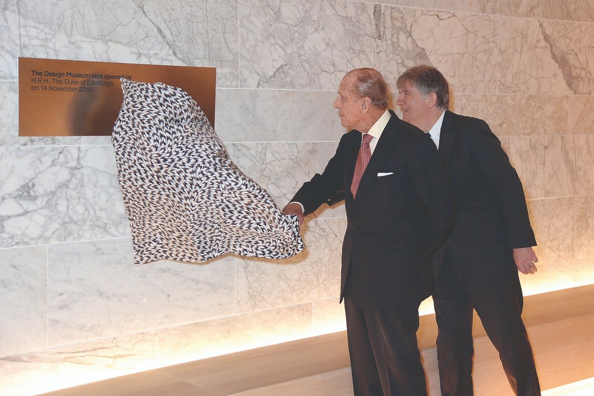 3/4 A milestone moment | The Duke of Edinburgh pulls back an Eley Kishimoto fabric cover to unveil the plaque to commemorating the opening of the new Design Museum, a listed 1960s London landmark in the heart of Holland Park.