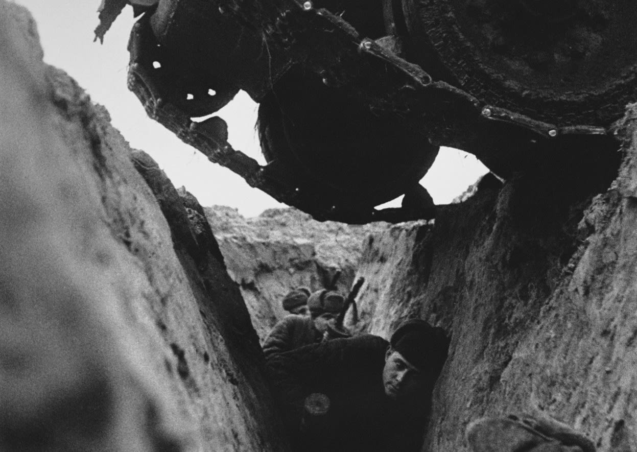 Red Army soldiers in a trench as a Russian T-34 tank passes over them in 1943, during the Battle of Kursk
