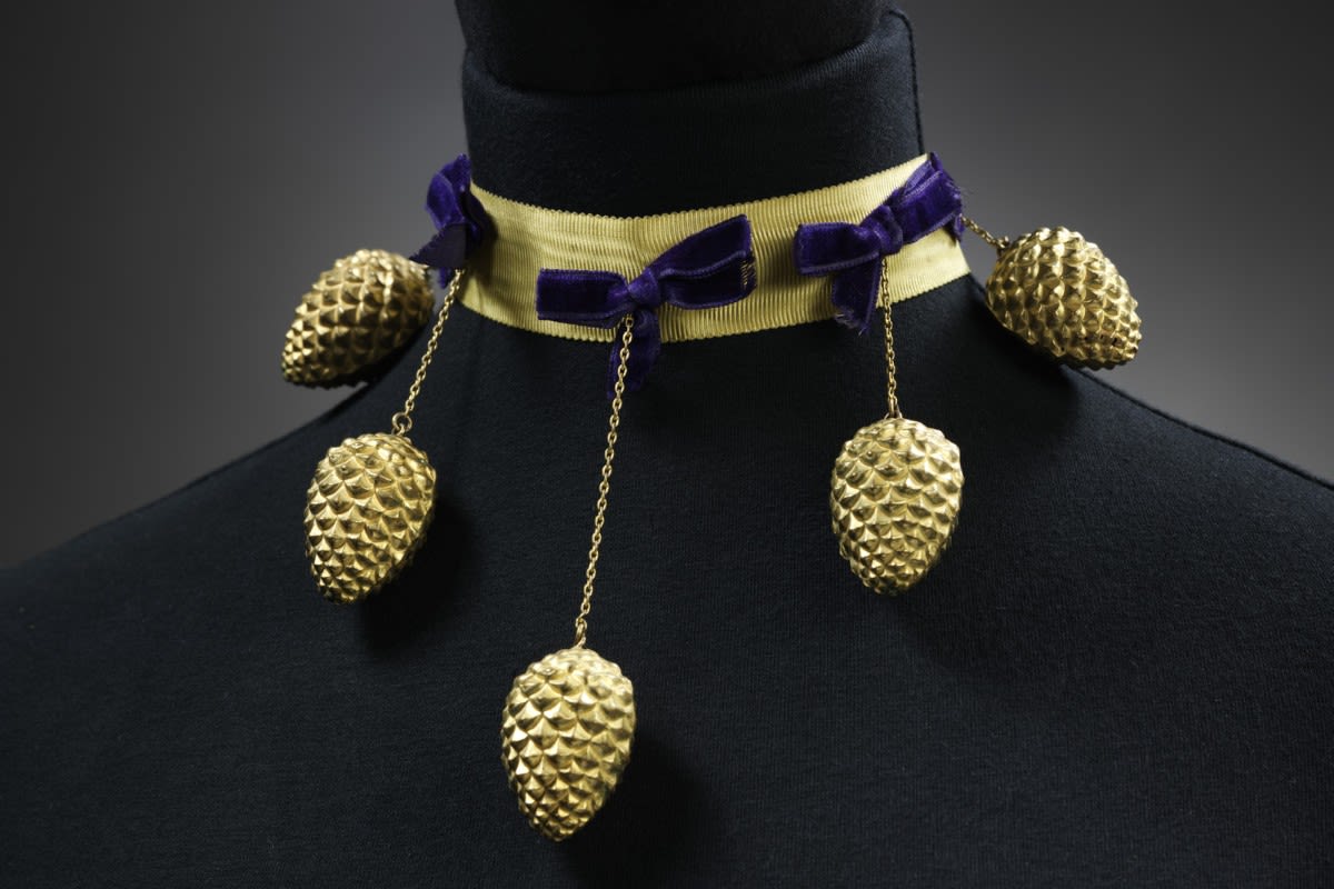 Elsa Schiaparelli's Pagan Collection from 1938 featured themes drawn from nature. Famous for her and unexpected surreal touches, as demonstrated by this dramatic necklace which sets purple velvet bows with a gilt pine cone suspended on a thin chain.