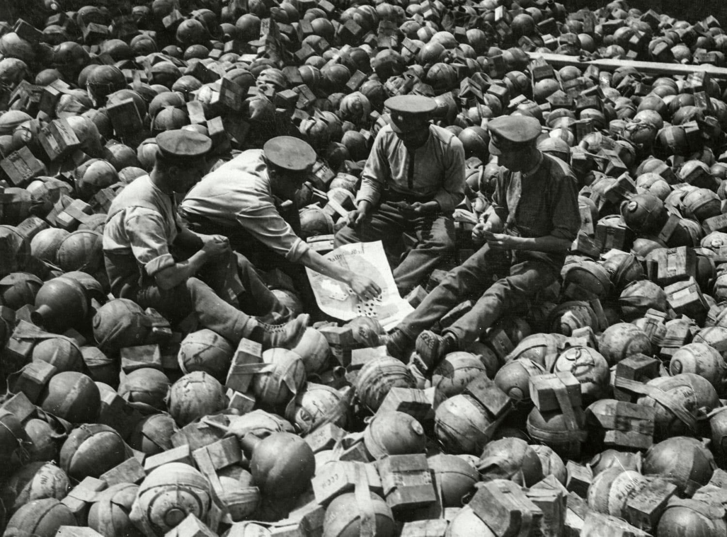 July 19, 1916: British soldiers playing cards on a large pile of trench mortar shells near Archeux, France, on the Western Front during WWI.