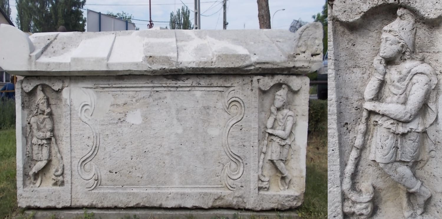 Roman sarcophagus at the city hall parking lot in Pomáz, Hungary, 3rd century CE. Pointed caps indicate foreigners of Asia and the Balkans, so the carved figures might show pride with Germanic ancestry. Or they may be the twins from the cult of Mithras, symbolizing the rising/setting sun