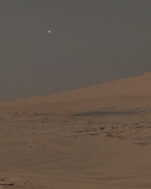 Moonset over Mars -- Phobos sets behind Mount Sharp on Mars. The image was captured by Curiosity's Mastcam in April 2014 and processed by Justin Cowart.