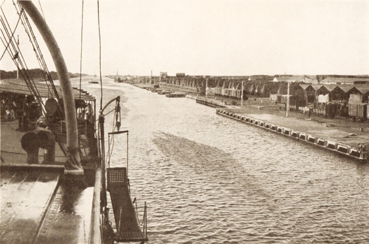 A steamer passes down the Suez Canal past the outpost of Kantara, Egypt. Just a few years ago this was empty desert, but the town exploded in size when it became the central supply depot for the British Army's Palestine force.