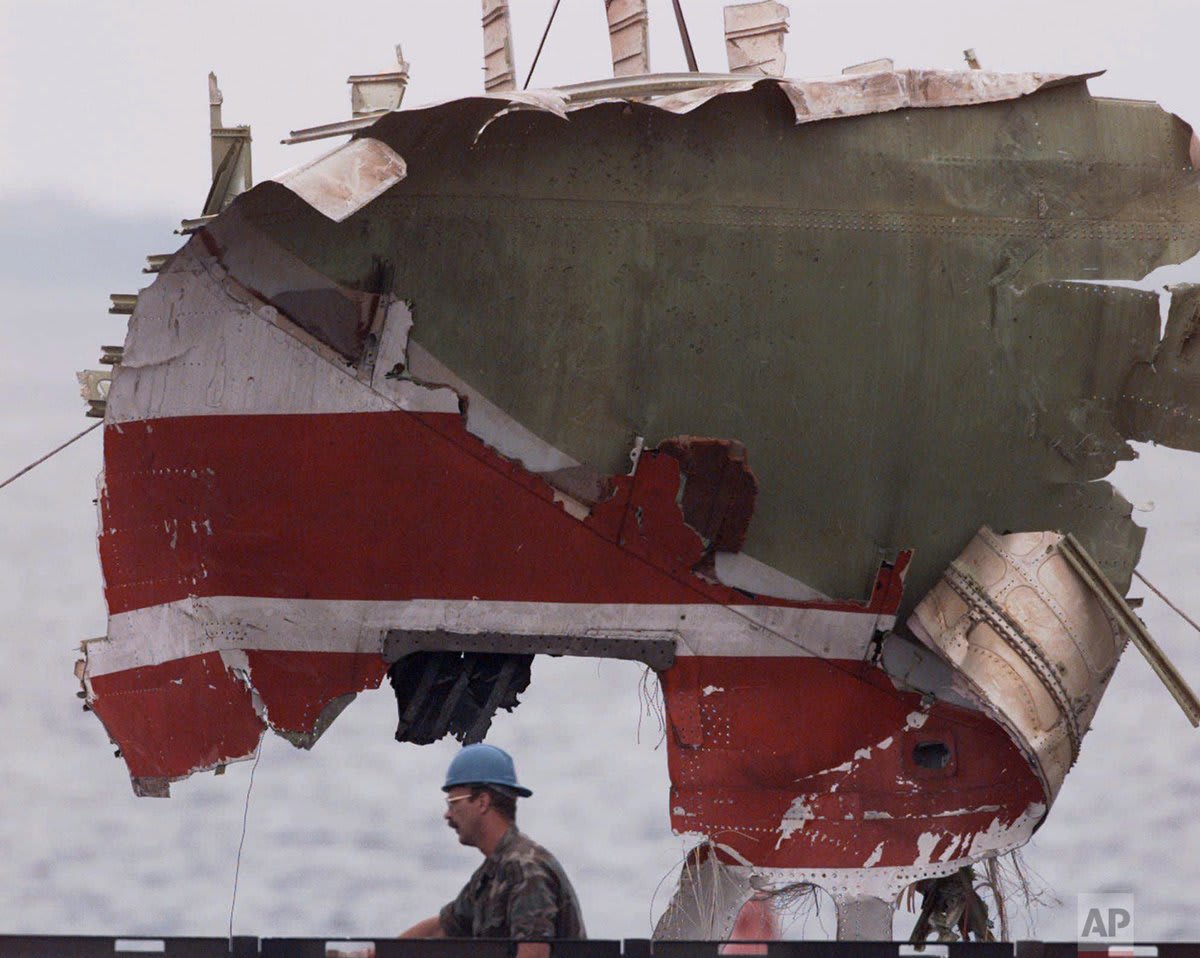 25 years ago today, TWA Flight 800, a Europe-bound Boeing 747, exploded and crashed off Long Island, New York, shortly after departing John F. Kennedy International Airport, killing all 230 people on board. A worker helps guide a piece of wreckage onto a truck on July 29.
