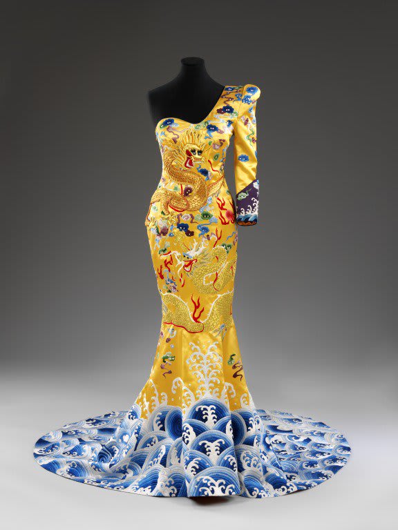 The beauty is in the detail. This show stopping yellow satin silk dress by designer Laurence Xu merges contemporary design and whilst nodding to tradition and Chinese craftsmanship. Can you spot the dragon robe motifs on the garment?