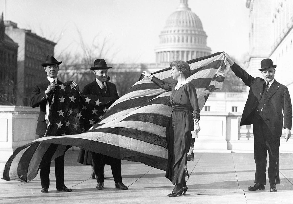 Congresswoman Jeannette Rankin is presented with the flag that flew at the House of Representatives during the passage of the suffrage amendment in 1919.