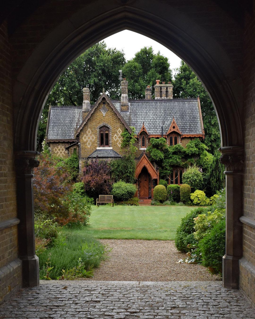 Victorian Gothic cottage beyond the arch of the gatehouse in Holly Village, Highgate, North London, UK.
