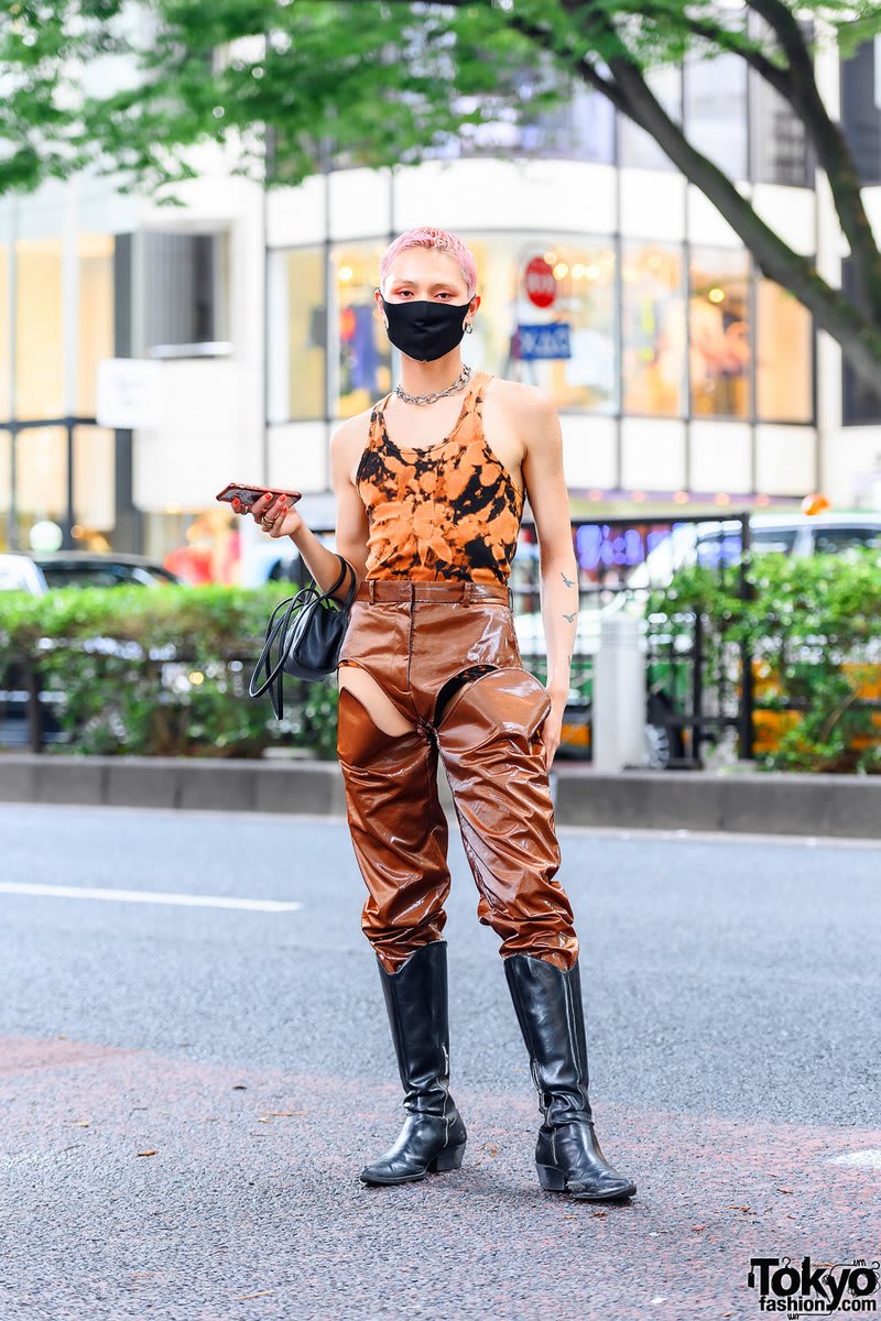 Pink-haired Japanese male model Minori on the street in Harajuku wearing Y/Project patent cutout pants with a dyed bodysuit, a Telfar bag, chain choker, and vintage leather boots