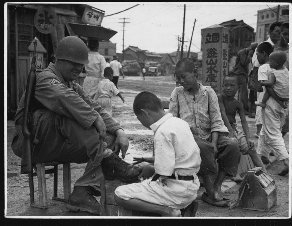 An American sergeant is seen having a shoe shine by a South Korean boy after his arrival in the town of Pusan, 1950.