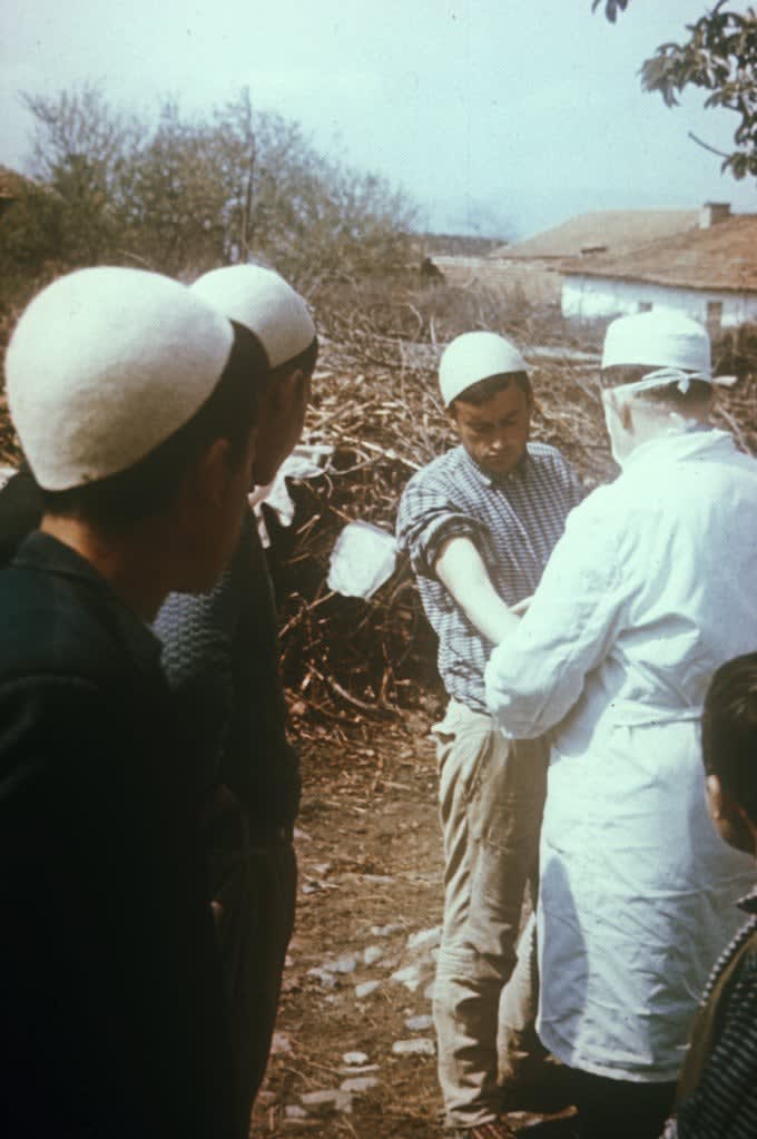 Field physicians checking an immunization reaction in a man vaccinated during smallpox epidemic. Kosovo, SR Yugoslavia. 1972