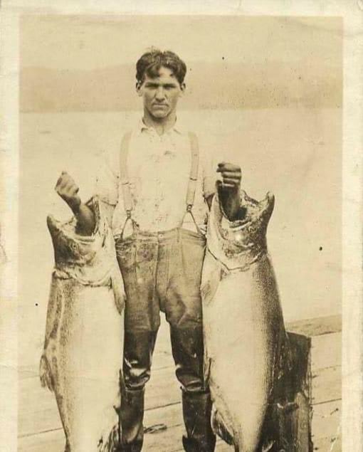 Man in Waldsport, Oregon holding aloft two Chinook Salmon he boasts he caught with his bare hands.