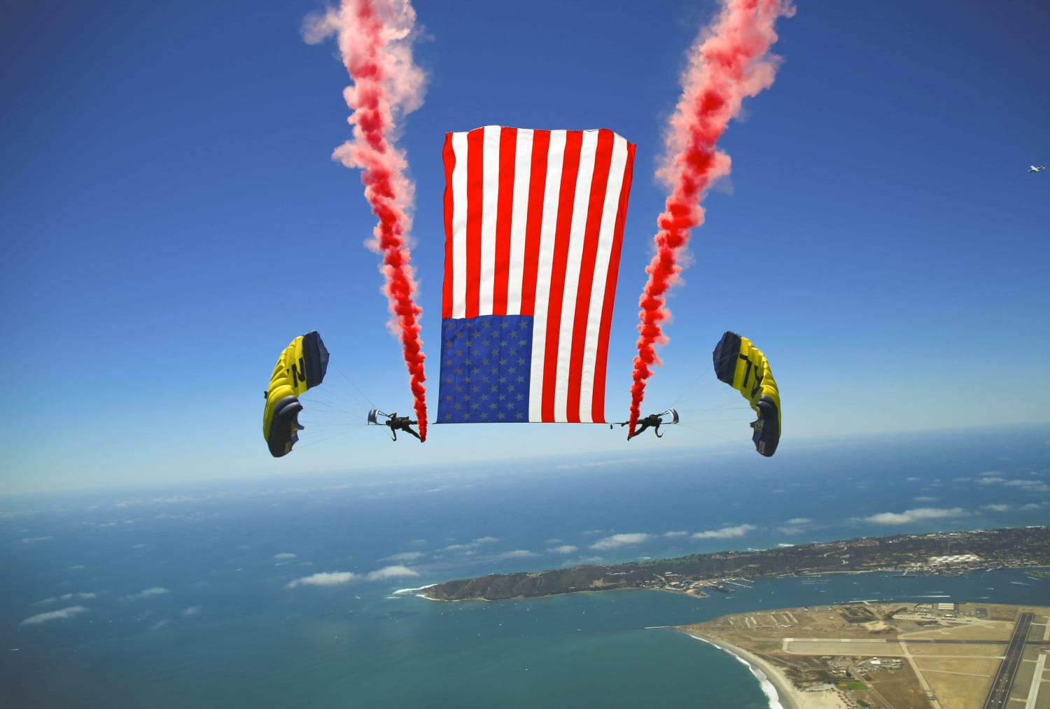 In it together! Members of the Navy Leap Frogs perform a tethered flag with smoke brackets over San Diego.