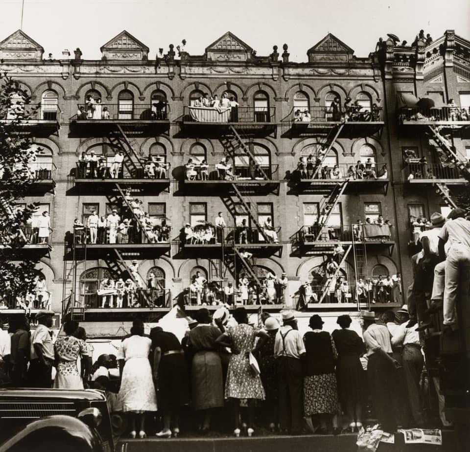 1938. Harlem. Residents on the street, fire escapes and roofs viewing the Harlem Elks Parade. Jack Manning, photographer