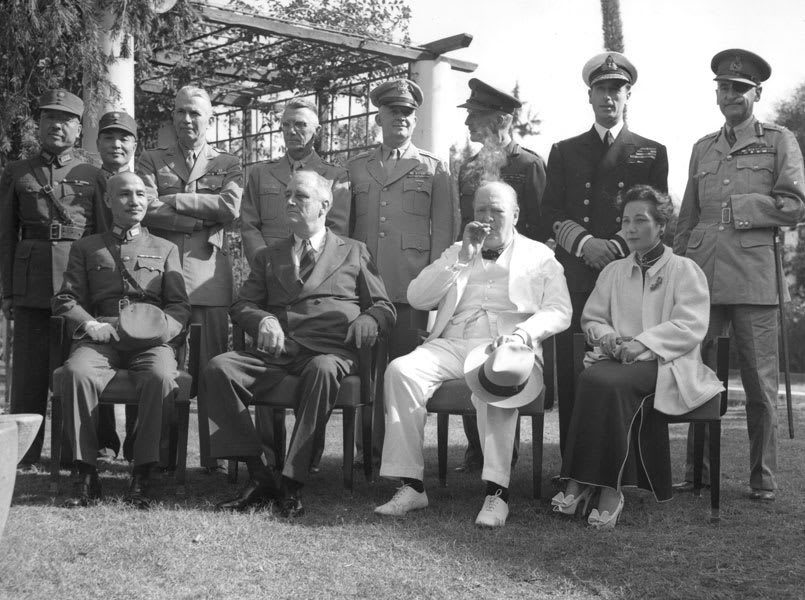 Chiang Kai-shek (seated, left) and Soong Mei-ling (seated, right), and Winston Churchill (in a white suit and puffing on a cigar), and others, attend the Cairo Conference in 1943.