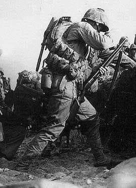 A Marine on Blue Beach 2, Okinawa (1 April 1945) is armed with a Winchester Model 12 trench gun as assault troops of the 1st Battalion, 7th Marines go over a seawall after landing unopposed.