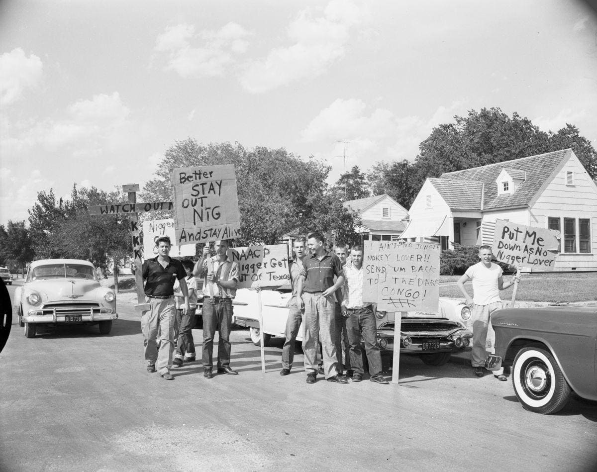 Residents of the Riverside neighborhood of Fort Worth, Texas are seen demonstrating in front of the house of Lloyd G. Austin, an African American man, who had recently moved in to the all-white neighborhood. (1956)