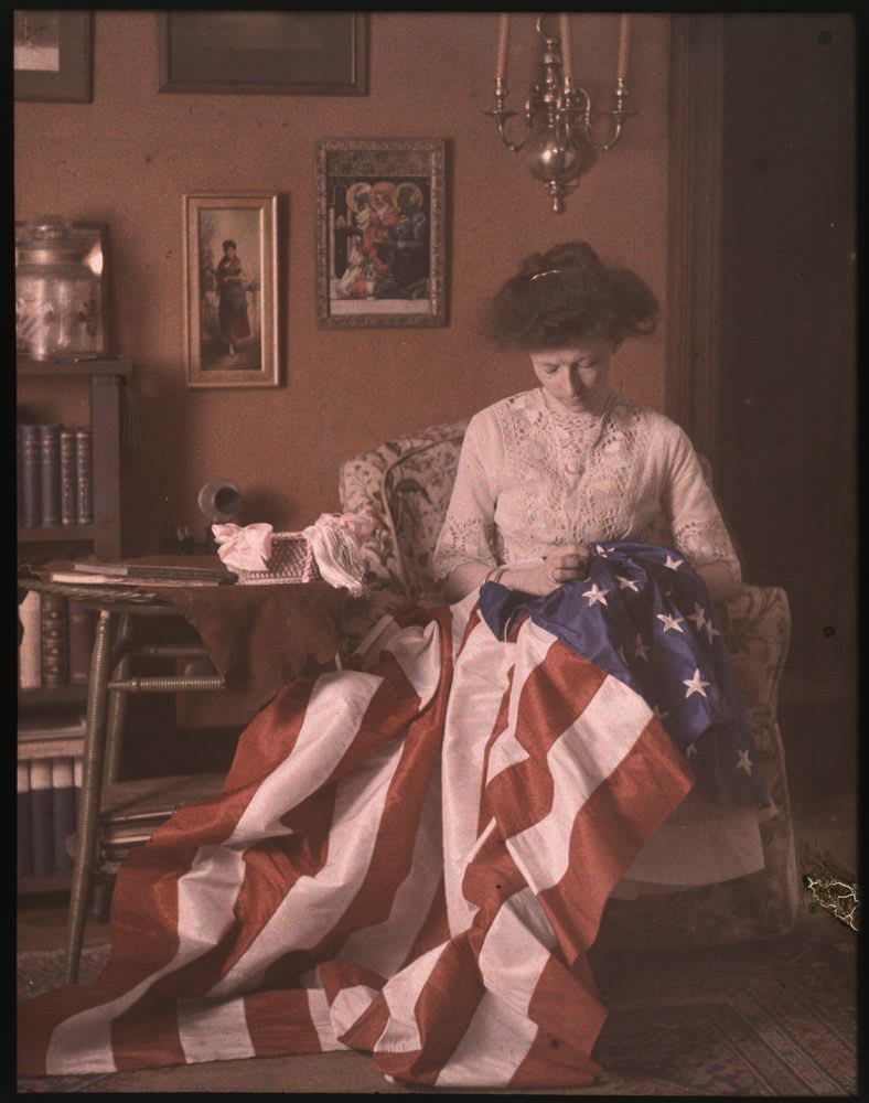 Happy 4th of July! Beautiful circa 1910 autochrome of a woman identified as Mrs. Benjamin F. Russell stitching an American flag, part of the Louis Walton Sipley collection.