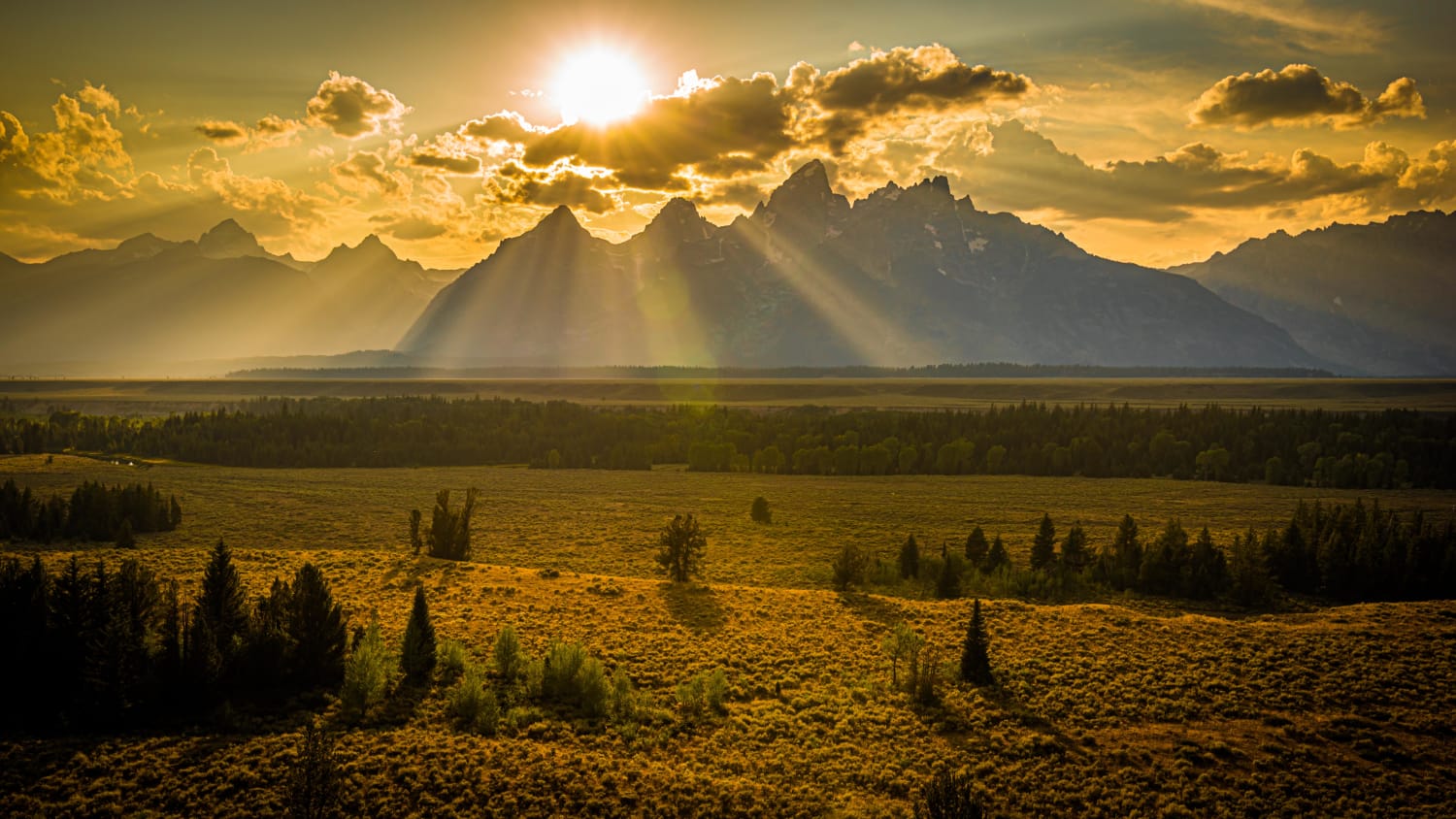 Setting sun painting the landscape behind the Grand Tetons, Jackson, WY.