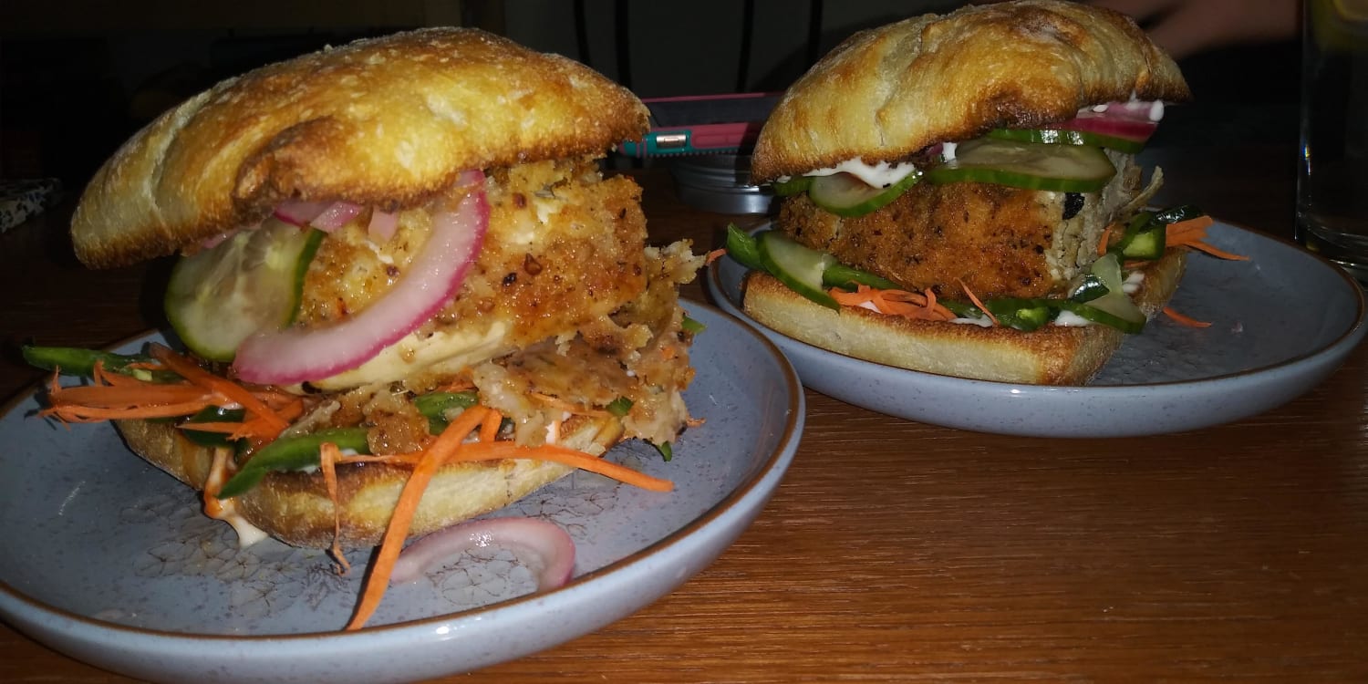 Fried chicken sando on ciabatta with pickled red onion, wasabi agave quick pickles, jalapeno, carrot, and sriracha mayo
