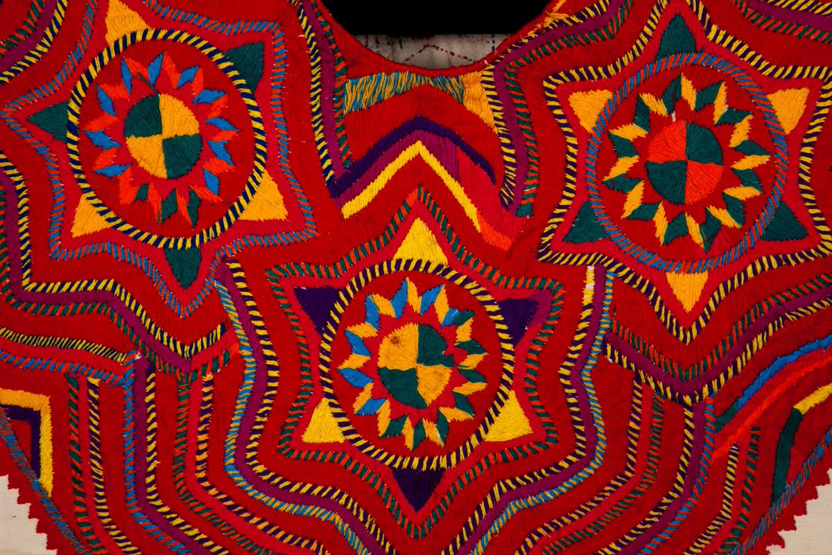 A huipil is a traditional blouse worn by indigenous women in Mexico and Central America. This huipil from San Mateo Ixtatán, Guatemala dates between 1960-1974. The neckline uses intricate embroidery to create a mesmerizing multicolored design