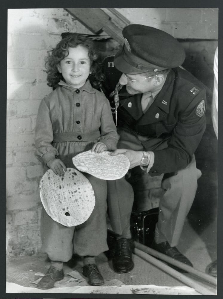 ChagSameach and #HappyPassover! A young liberated Jewish girl in the JDC-supported Berlin-Mariendorf DP Camp enjoys some matzah with Captain J. Robbins, Jewish Chaplain for Berlin, c1946.