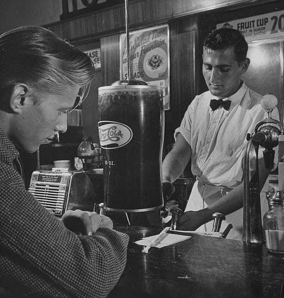 Soda fountain clerk serving a customer during Pepsi Cola equipment installation test at unaddressed drugstore in Manhattan (1947). Photo by Jerry Cooke/Getty Images