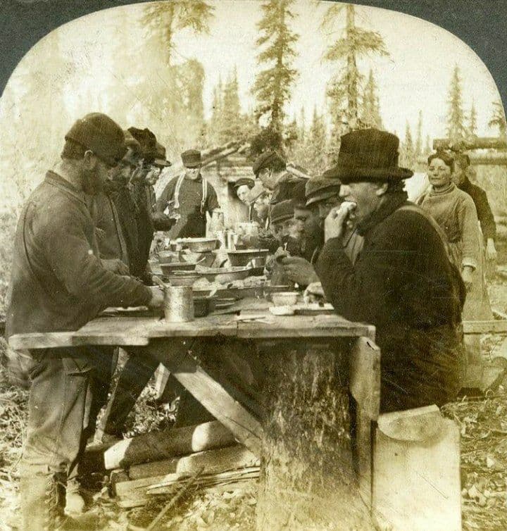 A Miner's Banquet: A group of Alaskan miners sharing a meal in Beaver City, Alaska. Sometime between 1897 and 1900.