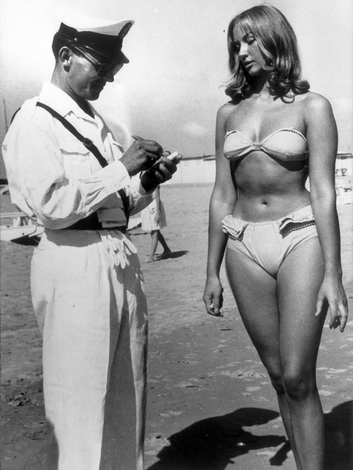 A police officer issuing a woman a ticket for wearing a bikini on a beach at Rimini, Italy, in 1957.