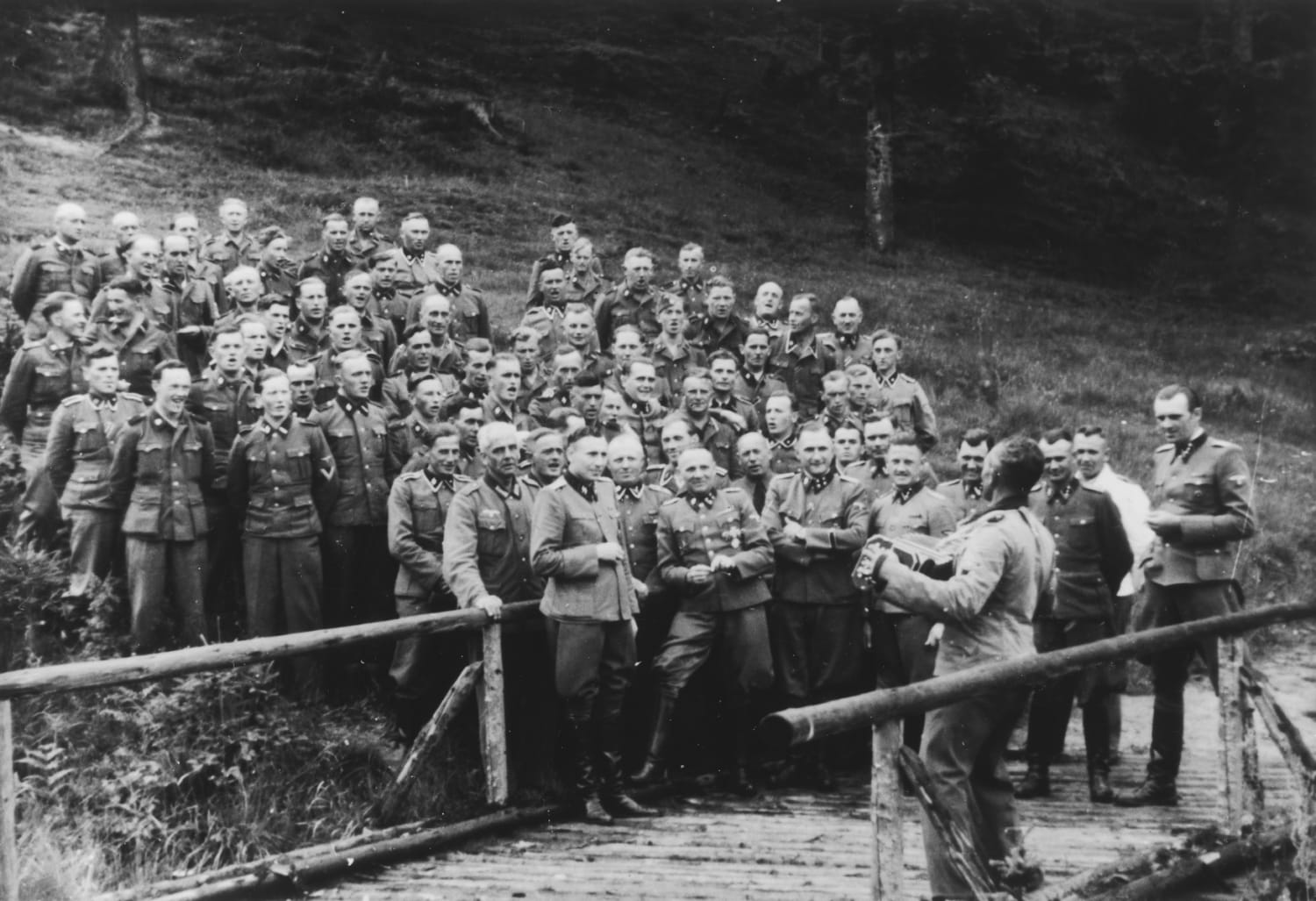 An accordionist leads a sing-along for SS officers at their retreat outside Auschwitz. The men in the front row, which include Rudolf Höss and Josef Mengele, were responsible for killing millions. Another, Otto Moll, burned infants alive and is suspected of over 20,000 murders, 1944 .