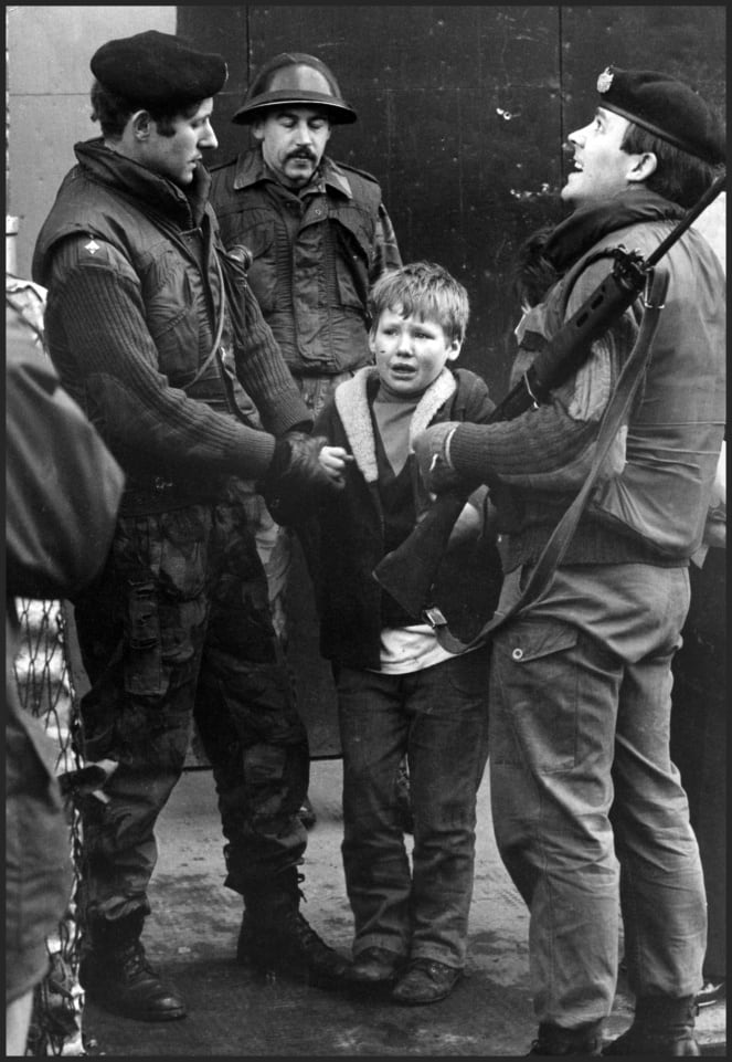 A young boy is held by British soldiers from the Gloucester Regiment after he was caught hurling stones at a Saracen Armoured Personal Carrier in the IRA stronghold, March 1972.
