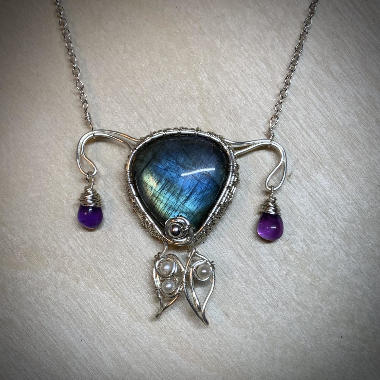 I made an uterus necklace with sterling silver wire, labradorite gemstone, and amethyst beads.