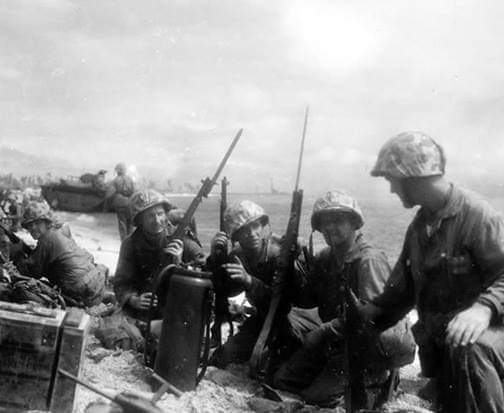 Roi, Namur. Marines regroup on the beach head after landing. The Marine looking at the camera carries a M97 Trench Model shotgun with bayonet attached.