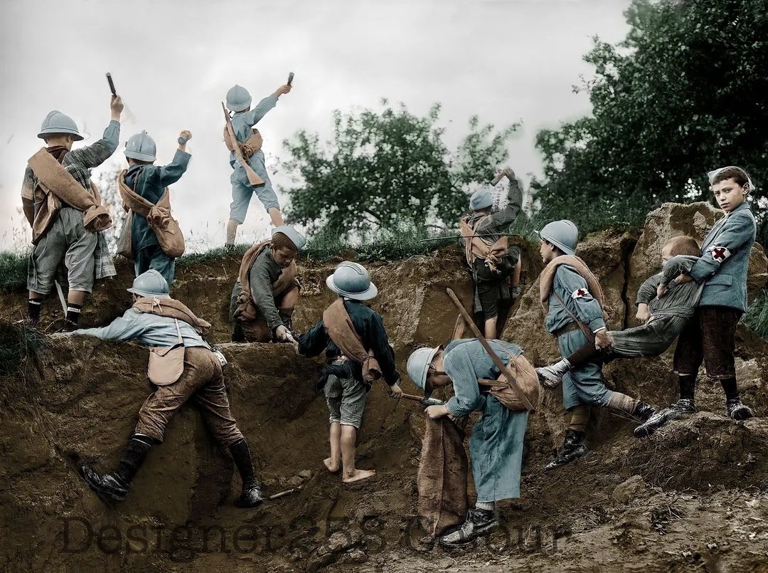 French children playing frontline soldiers with full equipment and their own trench, 1917. [Colorization]