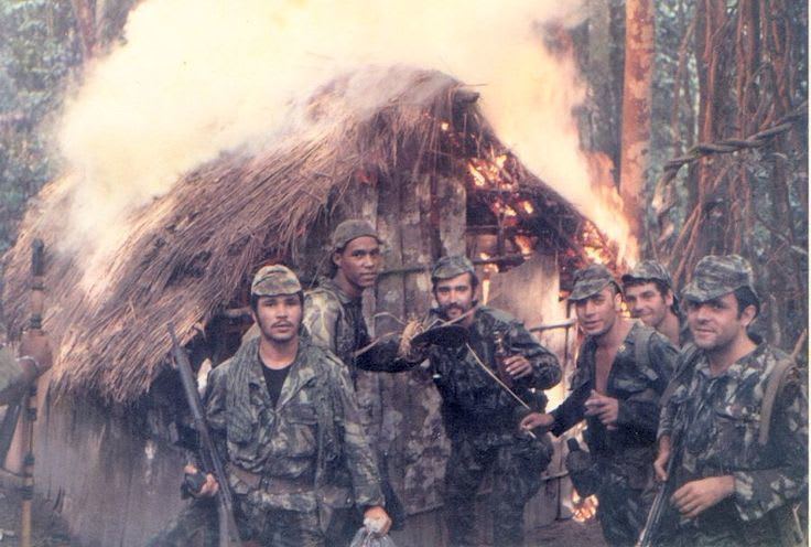 Portuguese soldiers pose in front of a torched hut belonging to suspected guerilla fighters. Angolan War of Independence, Angola, 1973.