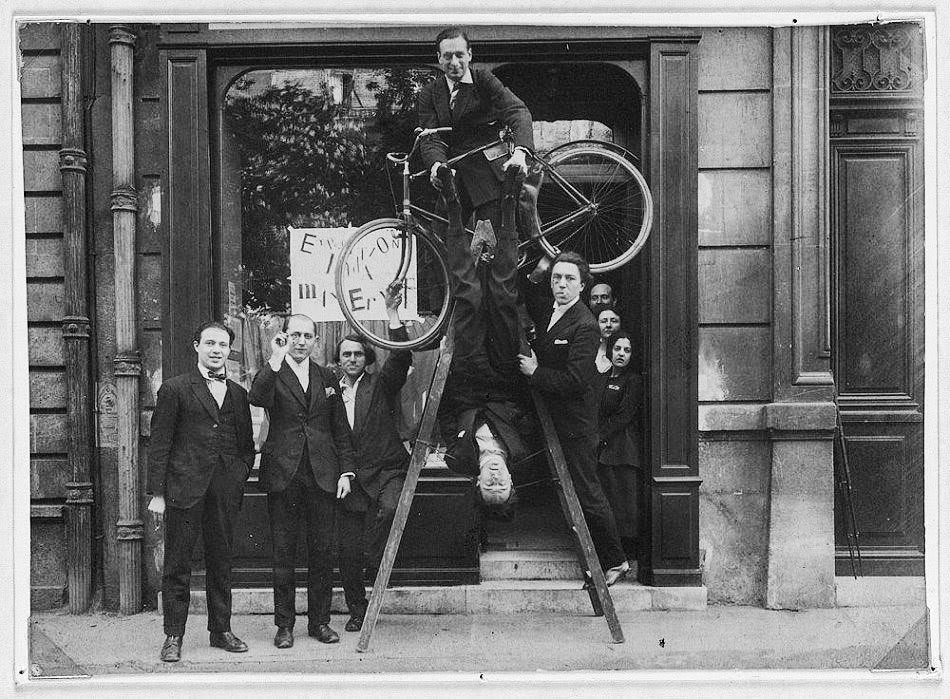 Opening of the exhibition Dada Max Ernst at the gallery Au Sans Pareil in Paris. Left to right: René Hilsum, Benjamin Péret, Serge Charchoune, Philippe Soupault (at the top of the ladder), Jacques Rigaut (upside down), and André Breton.