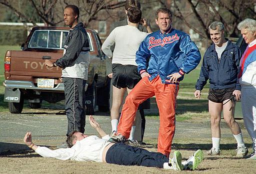 George Bush Jr. and his father President George Bush, as the President attempts to stretch prior to jogging at Fort McNair, 1990.