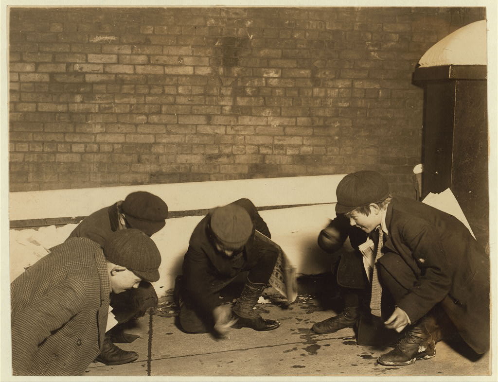 A group of newsies playing craps in the jail alley at 10 P.M. Albany, New York (State), February 1910 - By Lewis Hine for the National Child Labor Committee.