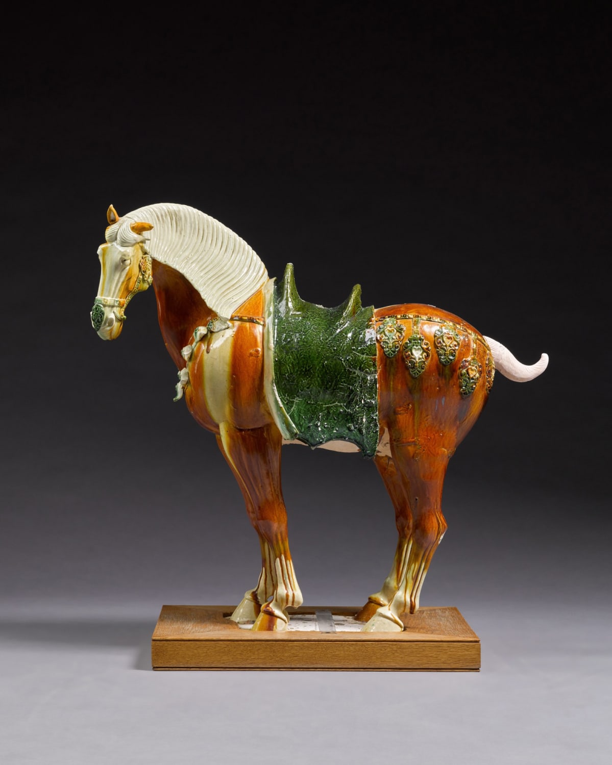Ceramic figure of a caparisoned Ferghana horse with sancai glaze and textured saddlecloth. China, Tang Dynasty (618-907 CE).