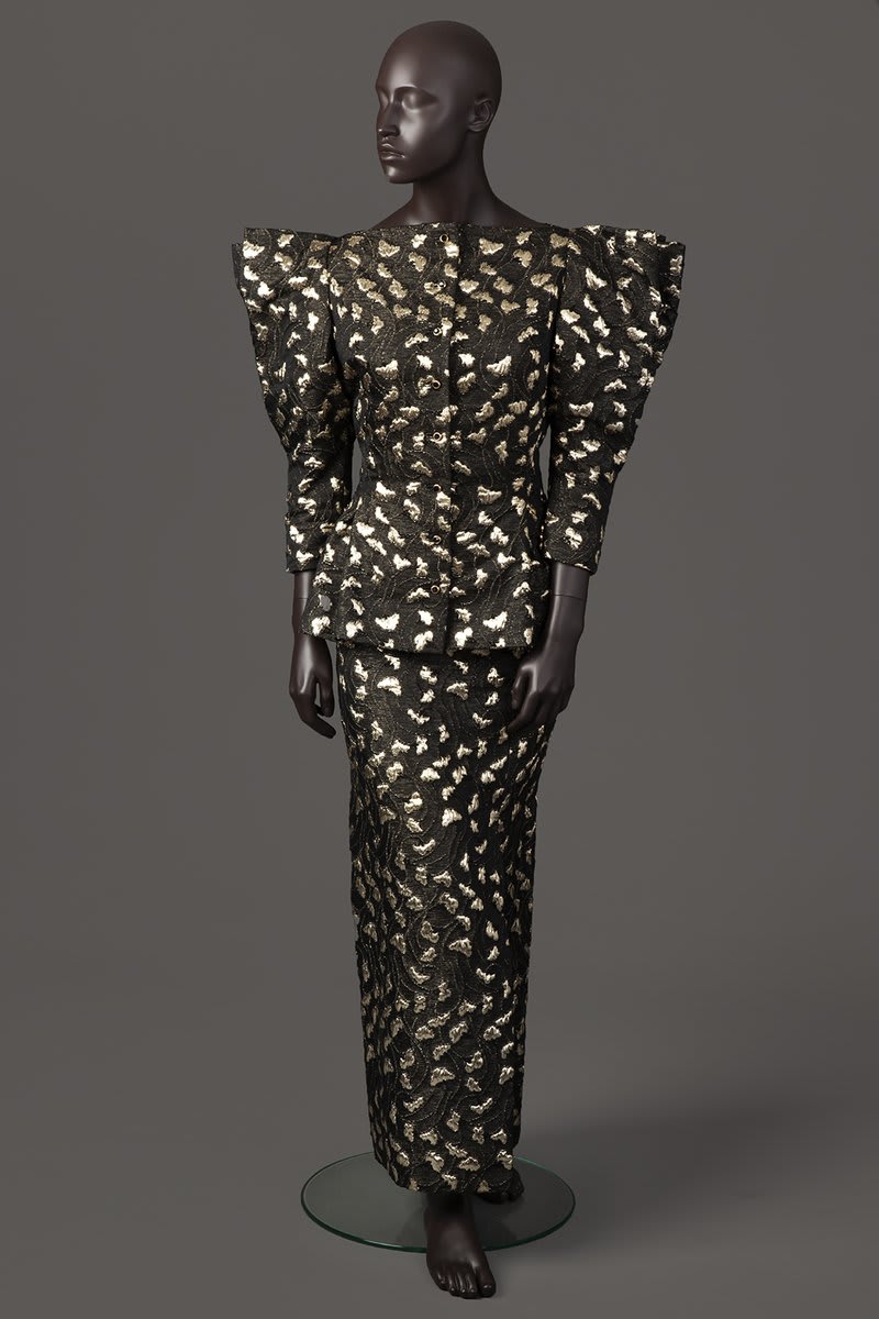Did you guess what it is? It's a gold & black brocade evening suit by Pauline Trigere, 1986. Check out those fab pleated sleeves! This ensemble was the 1st to be photographed on our new ethnically diverse mannequins, filling the gap in representation in museums