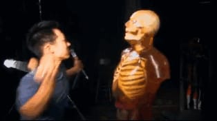 Man fighting a dummy with knitting needles.