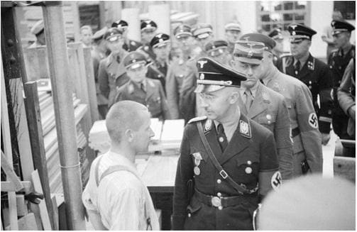 SS leader Heinrich Himmler confronts a political prisoner in the Dachau workshops during an official inspection of this “model” camp by Nazi grandees on May 8, 1936.