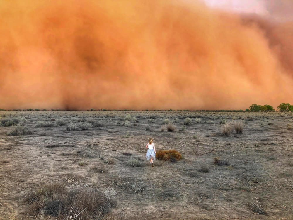 A child runs towards a dust storm in Mullengudgery, New South Wales, Australia. Dust storms have hit many parts of western New South Wales as a prolonged drought continues. Photo by: Marcia Macmillan/AFP/Getty Images