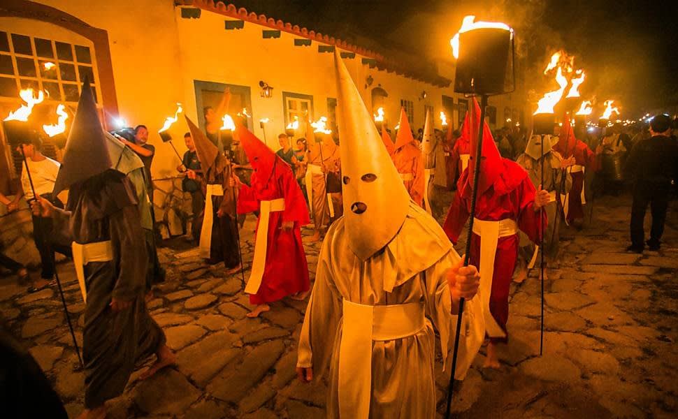 Not a Ku Klux Klan act. Since 1745 Catholics from a small Brazilian town dress like this and perform a ritual that symbolizes the sacrifice of Christ. The city lights are turned off and only the torches remain. They march in complete silence from one church to another while drums are played.