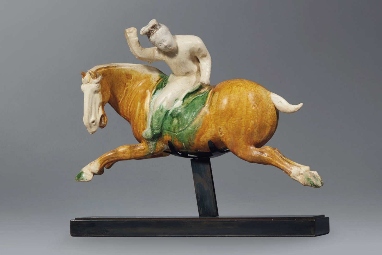 A very rare and important sancai-glazed pottery figure of a female polo player, Tang dynasty (AD 618-907). 13¾ in (35 cm) long